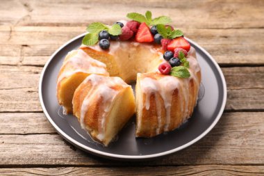 Lezzetli kek parçaları, böğürtlenli, jöleli ve naneli ahşap masa, yakın plan.