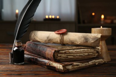 Eski parşömen, yanan mum, tüy, mürekkep hokkası ve ahşap masa üzerindeki kitaplar.