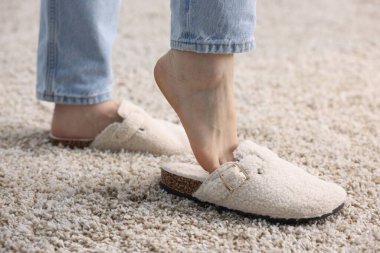 Beyaz terlikli kadın yumuşak halıda, yakın plan.