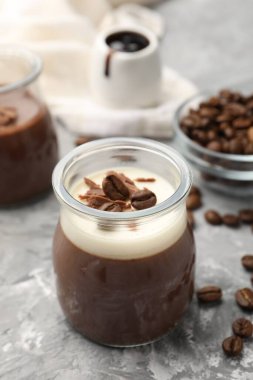 Çikolata parçalı lezzetli panna cotta ve gri desenli masada kahve çekirdekleri, yakın plan.