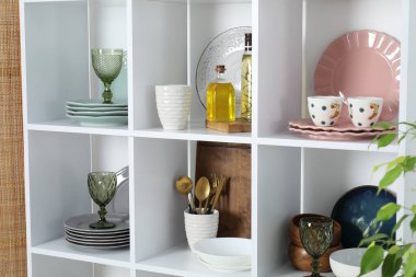 Farklı bulaşık takımları, bardaklar ve diğer mutfak gereçleri olan raf ünitesi.