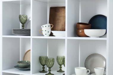 İçeride farklı bulaşık takımları, bardaklar ve bardaklar olan raf ünitesi