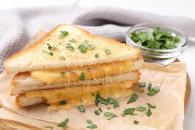 Eritilmiş peynirli lezzetli sandviçler ve beyaz masada maydanoz. Yakın plan.