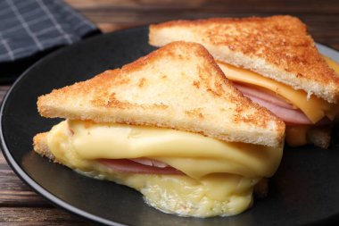 Eritilmiş peynirli ve ahşap masada jambonlu lezzetli sandviçler.