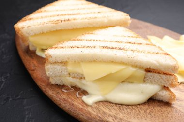 Eritilmiş peynirli lezzetli sandviçler gri desenli masada, yakın plan.