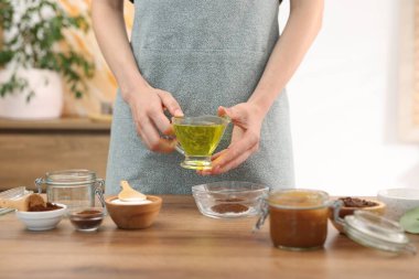 Doğal temizlik yapıyorum. Ahşap masada yağlı boya katan kadın, yakından.