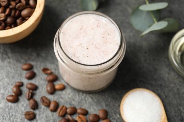 Doğal vücut fırçası cam kavanoz ve gri masa üzerindeki malzemeler.