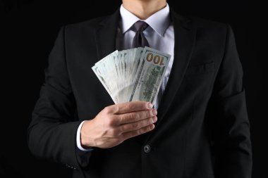 Siyah arka planda dolar banknotları olan adam, yakın plan.