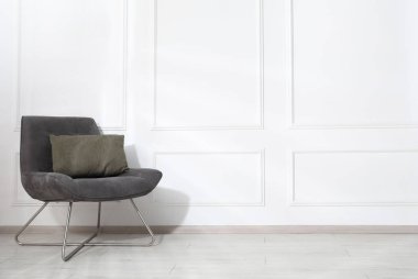 Beyaz duvarın yanında yastıklı rahat koltuk, metin için boşluk.