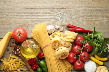 Farklı türde makarna ve malzemeler ahşap masada, düz yerde. Metin için boşluk