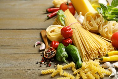Farklı türde makarna ve malzemeler ahşap masada, yakın plan. Metin için boşluk