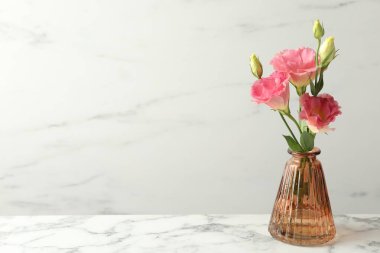 Beyaz mermer masa üzerinde cam vazoda güzel Eustoma çiçekleri, metin için yer