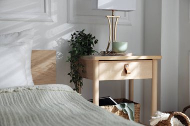 Yatağın içinde lamba ve diğer dekorlarla birlikte komodinin yanında.