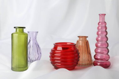 Beyaz kumaş üzerinde farklı güzel cam vazolar.