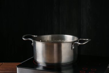 Mutfaktaki ocağın üstünde kaynar su bulunan metal tencere.