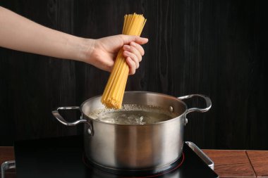 Mutfaktaki elektrikli ocakta makarna yapan kadın, yakın plan.