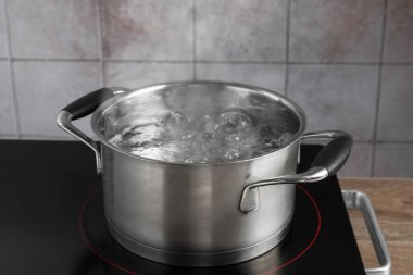 Mutfaktaki ocağın üstünde kaynar su bulunan metal kap, yakın plan.