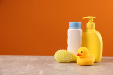 Bebek aksesuarları ve banyo ürünleri gri masada turuncu arka plana karşı, metin için yer