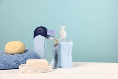 Bebek aksesuarları ve banyo ürünleri beyaz ahşap masa üzerinde açık mavi arkaplan, metin için yer