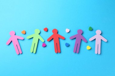 Hoşgörü konsepti. Renkli insan figürleri ve açık mavi arka planda kalpler, düz yatıyordu.