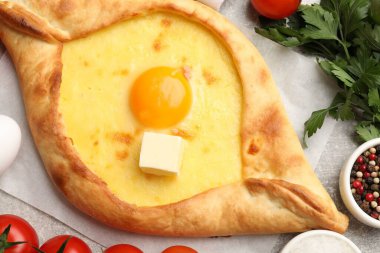 Açık gri zemin üzerinde peynir, yumurta ve diğer ürünler ile lezzetli khachapuri, düz yatıyordu