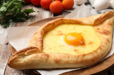 Lezzetli khachapuri peyniri, yumurtası ve diğer ürünleri ahşap masada, yakın plan.