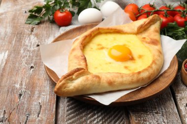 Lezzetli khachapuri peyniri, yumurtası ve diğer ürünleri ahşap masada, yakın plan.