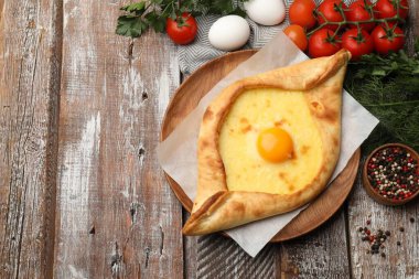 Peynirli, yumurtalı ve ahşap masadaki diğer ürünlerle nefis bir khachapuri. Metin için boşluk