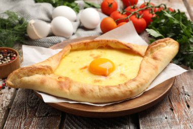 Lezzetli khachapuri peyniri, yumurtası ve diğer ürünleri ahşap masada, yakın plan.