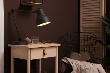 Bir bardak su, lamba ve gözlüklü ahşap masa.