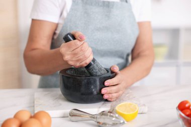 Üst düzey kadın mutfaktaki beyaz mermer masada yemek pişiriyor.