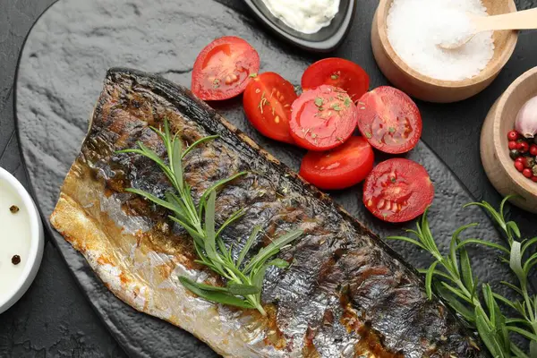Lezzetli kızarmış uskumru, siyah masada baharat ve sos ile servis ediliyor. Ev yapımı deniz ürünleri yemeği.