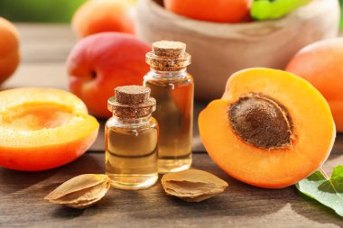 Şişelerdeki, tohumlardaki ve olgun kayısılardaki yağlar ahşap masada, yakın plan.