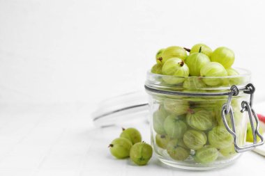 Taze yeşil bektaşi üzümleri kavanozda beyaz masada, yakın plan. Metin için boşluk