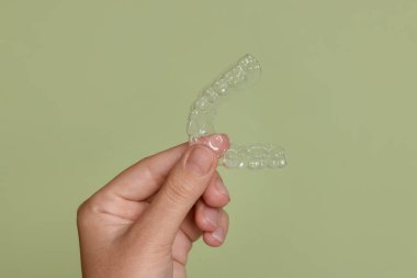 Yeşil arka planda diş hizalayan kadın, yakın plan.