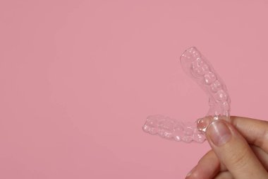 Pembe arka planda diş hizalayan kadın, yakın plan. Metin için boşluk