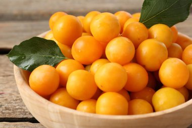 Olgun sarı kiraz erikleri ve yapraklar ahşap masada, yakın plan.