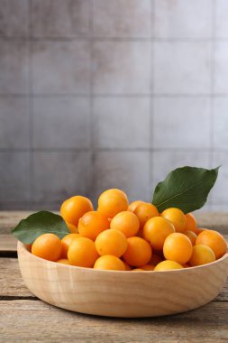 Olgun sarı kiraz erikleri ve ahşap masanın üzerindeki yapraklar. Metin için boşluk