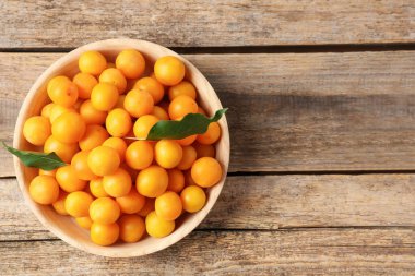 Olgun sarı kiraz erikleri ve yapraklar ahşap masanın üstünde, üst manzara. Metin için boşluk