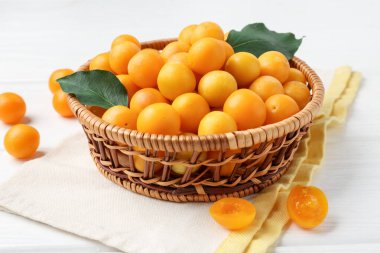 Beyaz ahşap masada yaprakları olan olgun sarı kiraz erikleri, yakın plan.