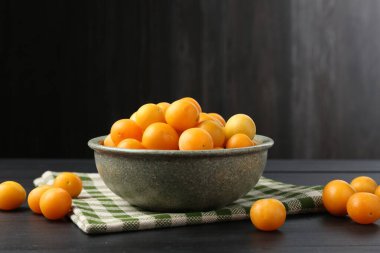 Siyah ahşap masada olgun sarı erikler.