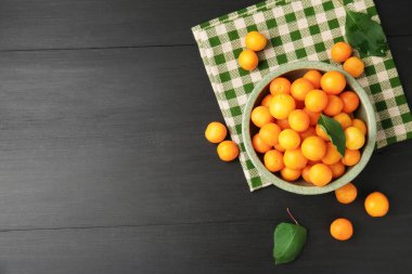 Siyah ahşap masa üzerinde yaprakları olan olgun sarı kiraz erikleri, düz yatıyordu. Metin için boşluk