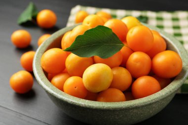 Olgun sarı kiraz erikleri Siyah ahşap masa üzerinde yapraklar, yakın çekim