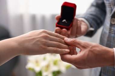 Nişan yüzüklü bir adam içeride kız arkadaşına evlenme teklif ediyor.