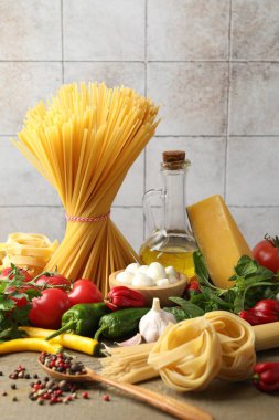 Farklı türde makarna ve malzemeler ahşap masada, yakın plan.