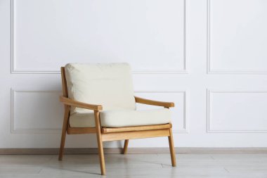 Beyaz duvarın yanındaki rahat bej koltuk.