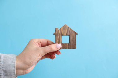 Ev güvenliği. Açık mavi arka planda ev figürlü kadın, yakın plan.