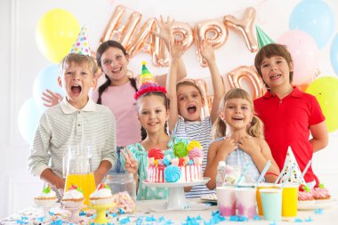 Doğum günü kutlaması. Masadaki çocuklar lezzetli pastalar ve dekoratif odalarda farklı şeyler yiyorlar.