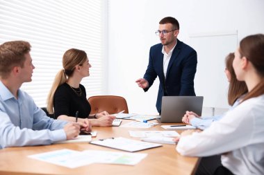 İş koçu ofisteki bir grup insana sunum yapıyor.