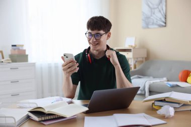 İyi bir sınav sonucunu kutlayan mutlu öğrenci içeride masada.